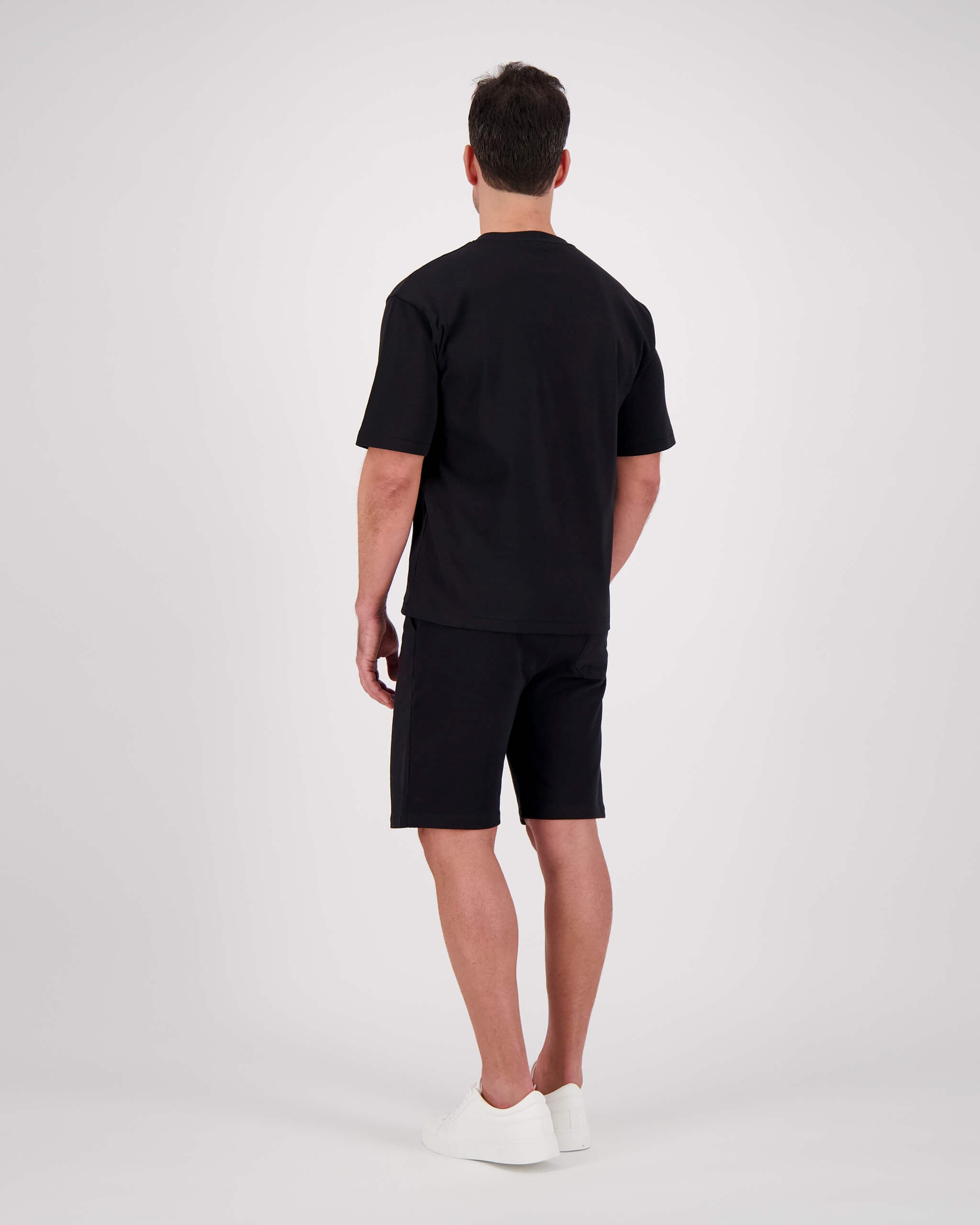 Rückseite Model posiert mit T-Shirt Paul für den Mann in der Farbe Schwarz